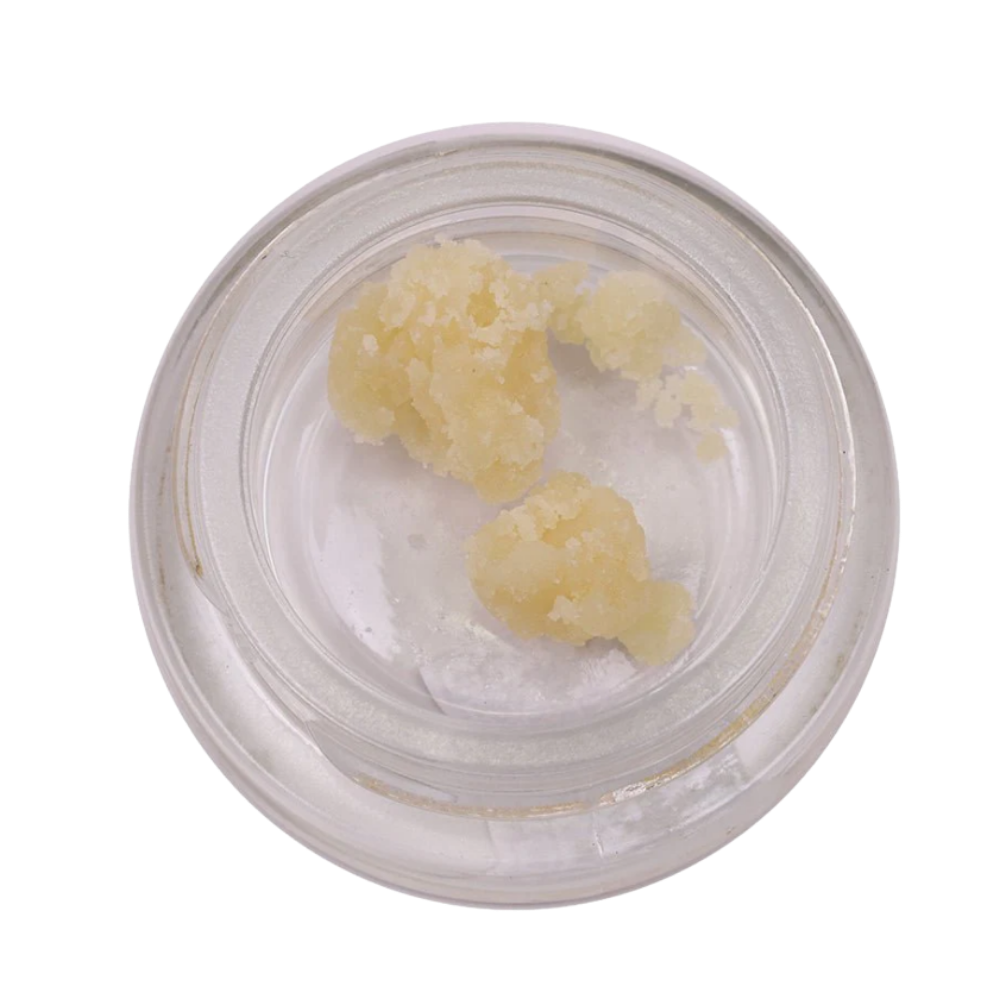Top-down view of a small glass jar containing pale yellow waxy lumps inside.
